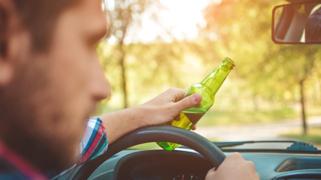 Image of a man drinking alcohol while driving which can result into a felony DWI lawsuit